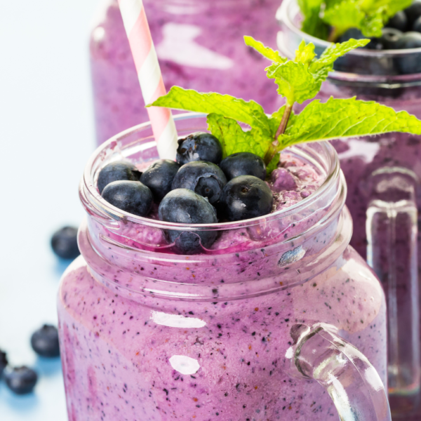 A delicious looking blueberry collagen smoothie in a tall glass.